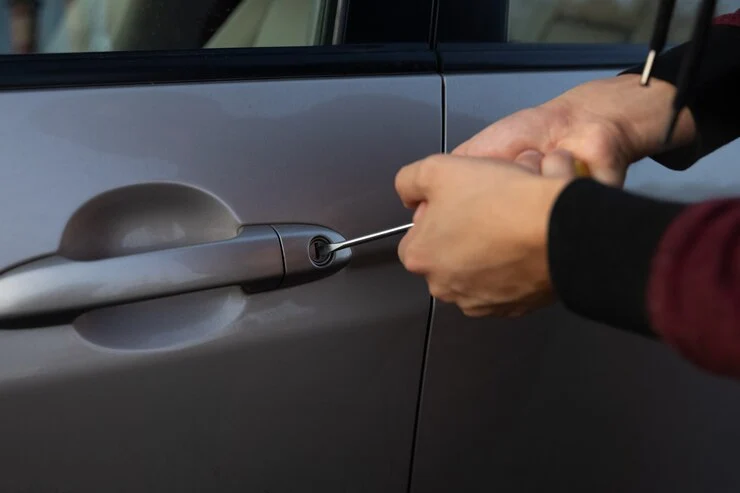 Låsesmed prøver å bryte opp bilens lås for å stjele den fra parkeringsplassen